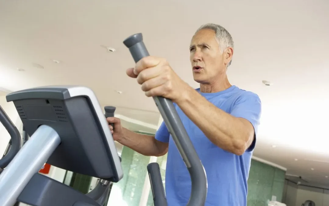 Älterer Mann trainiert auf einem Crosstrainer im Fitnessstudio