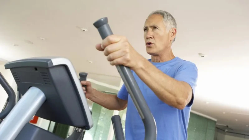 Älterer Mann trainiert auf einem Crosstrainer im Fitnessstudio