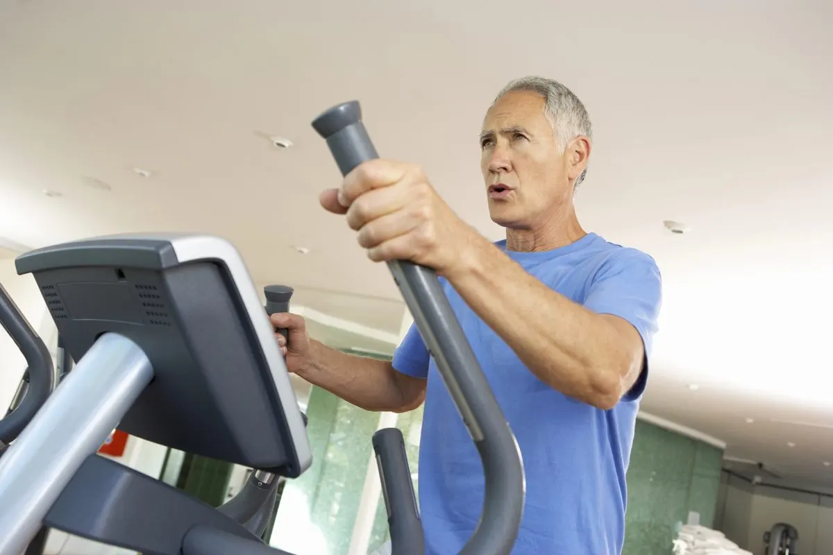 Älterer Mann trainiert auf einem Crosstrainer im Fitnessstudio