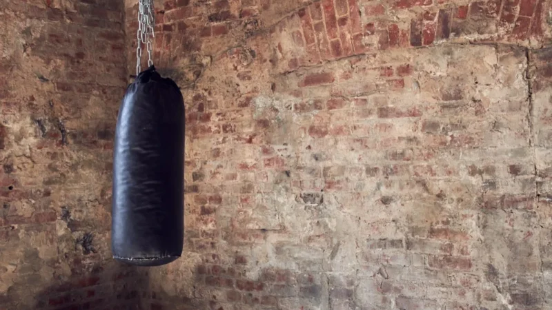 Hängender Boxsack vor einer Ziegelwand im Trainingsraum