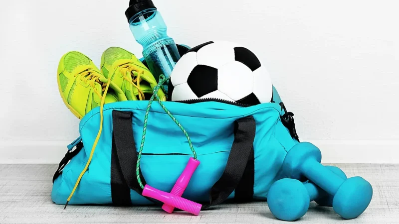 Sporttasche mit Laufschuhen, Kurzhanteln, Ball und Trinkflasche