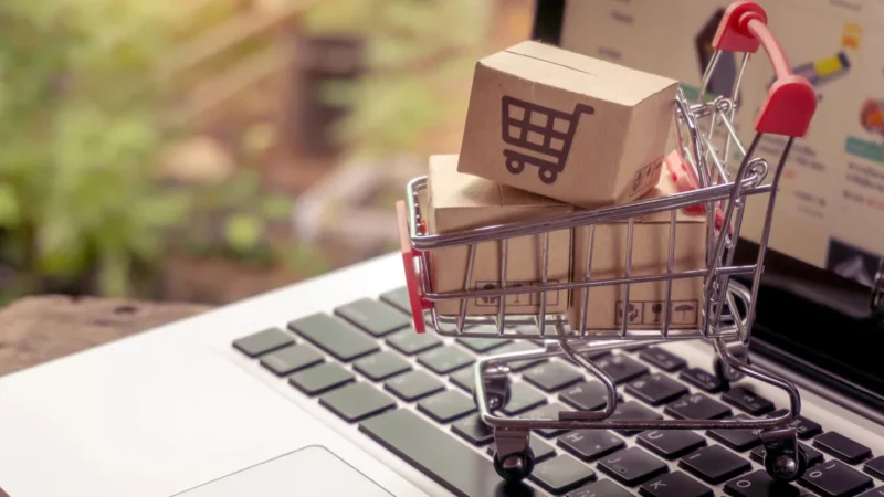 Einkaufswagen mit Paketen auf einem Laptop als Symbol für den Onlinekauf