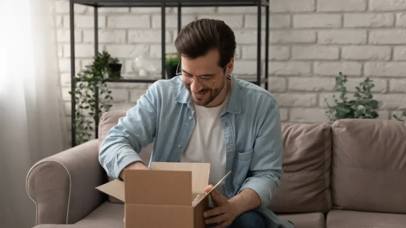 Mann packt zu Hause ein geliefertes Paket aus